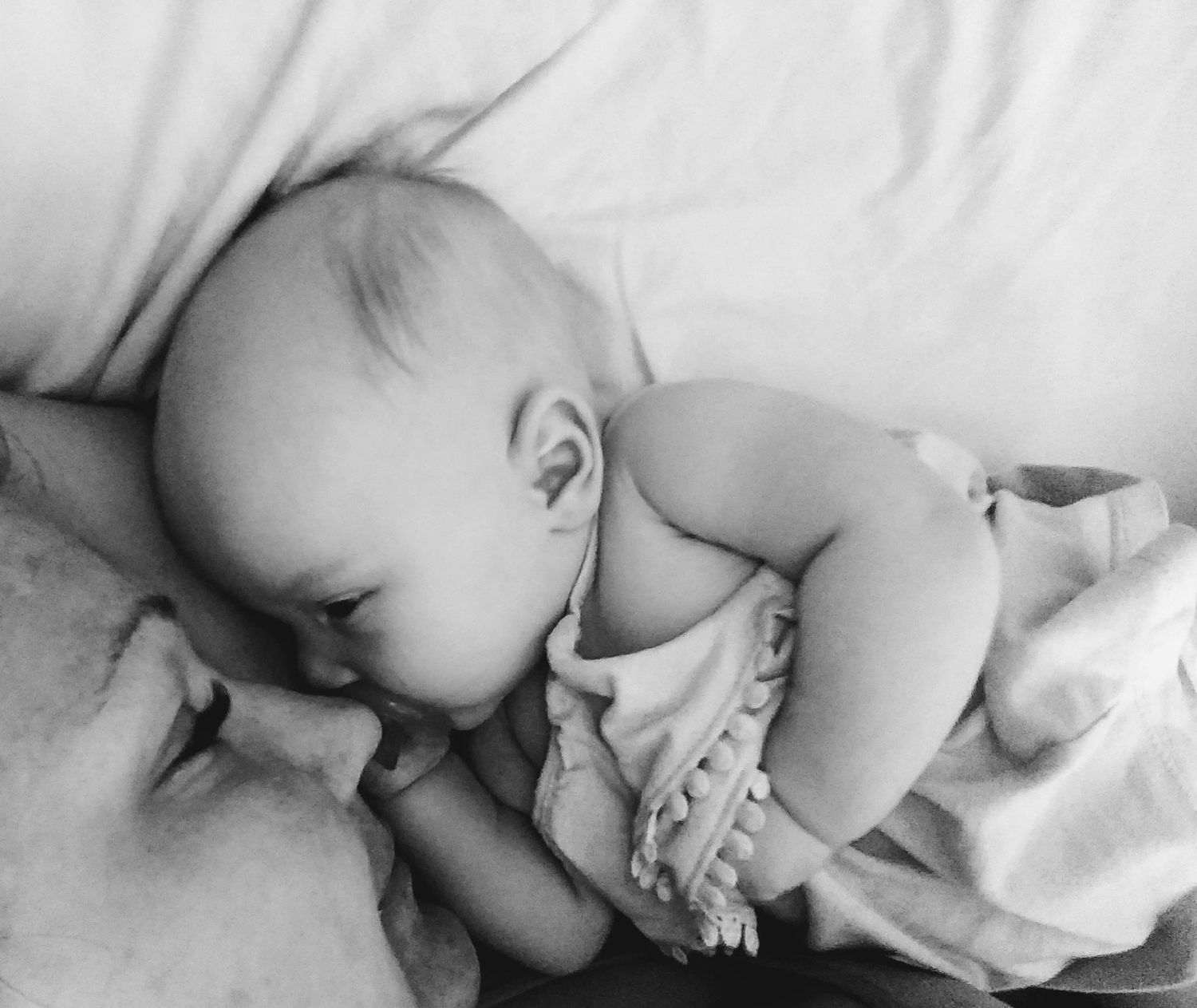 Babies in white clothing sleeping peacefully on white bedding.