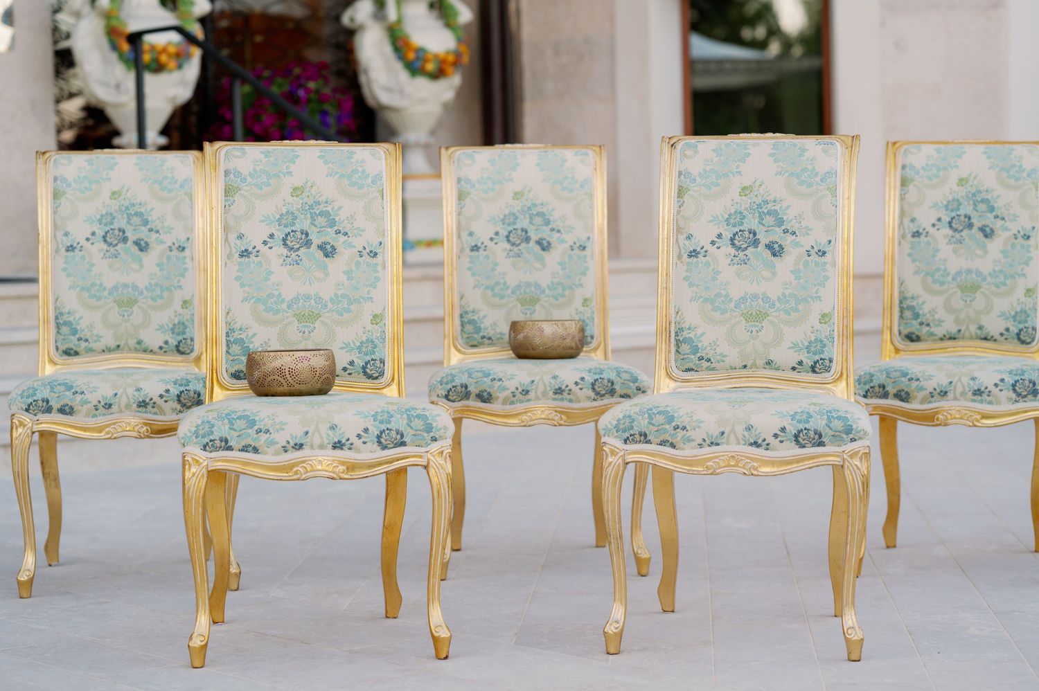 Row of elegant blue and gold French-style chairs arranged for a formal event.