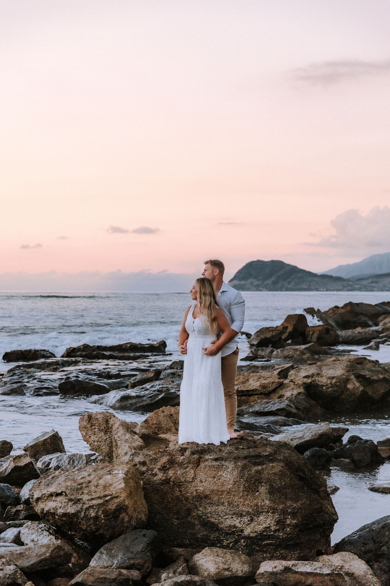 A romantic coastal portrait with dramatic rocky shoreline at sunset.