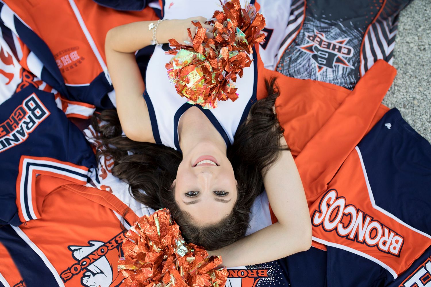 Cheerleader lying on university memorabilia in team colors.