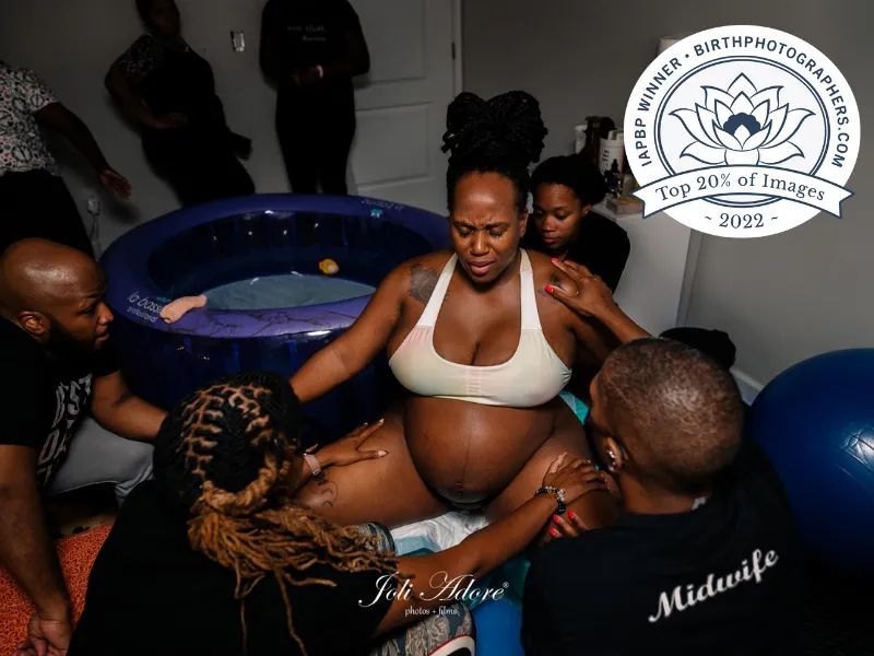 2022 iapbp birth competition winner - laboring woman wearing a sports bra sitting on birthing ball surrounded by family