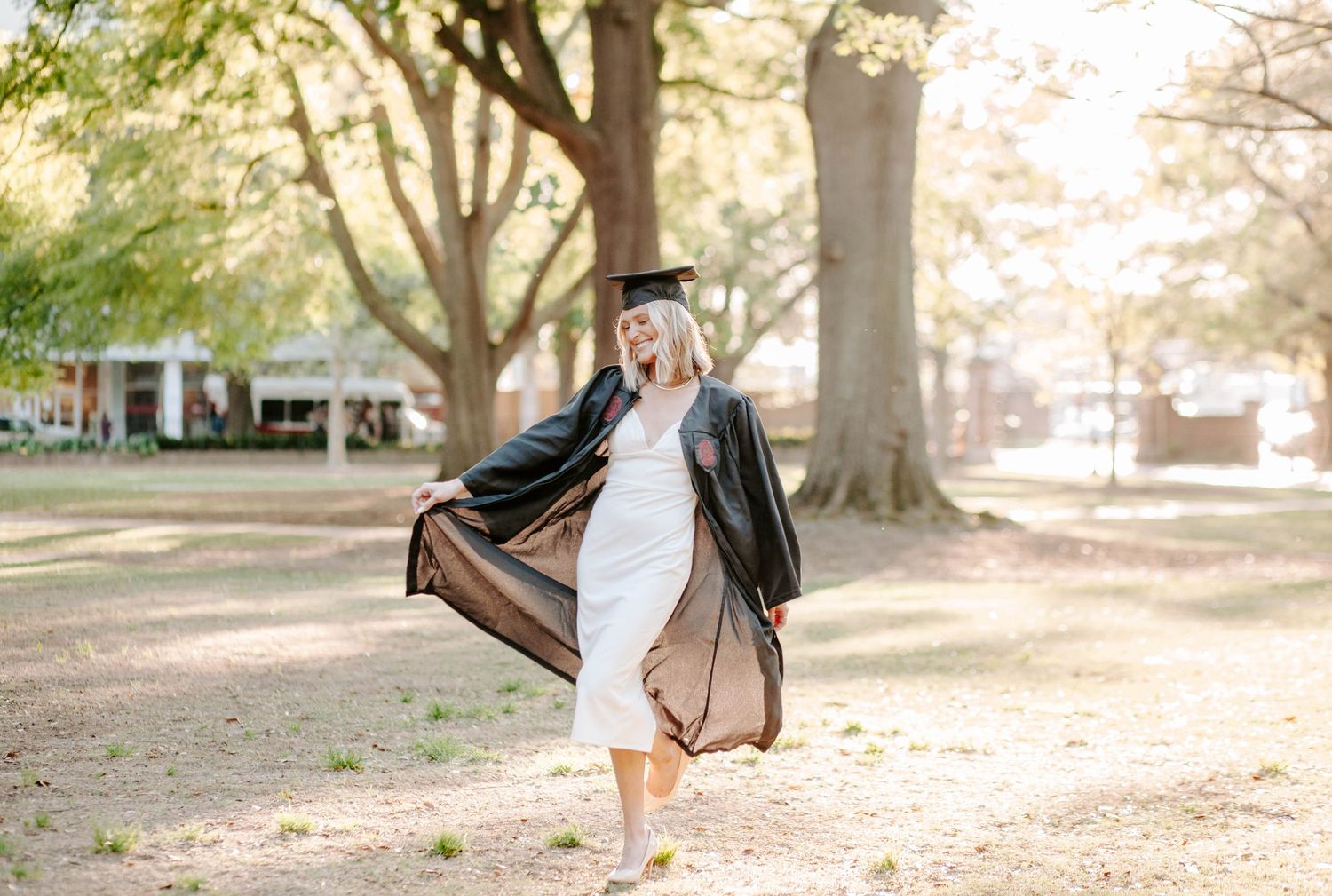 College graduate twirling around during golden hour in an open natural landscape.