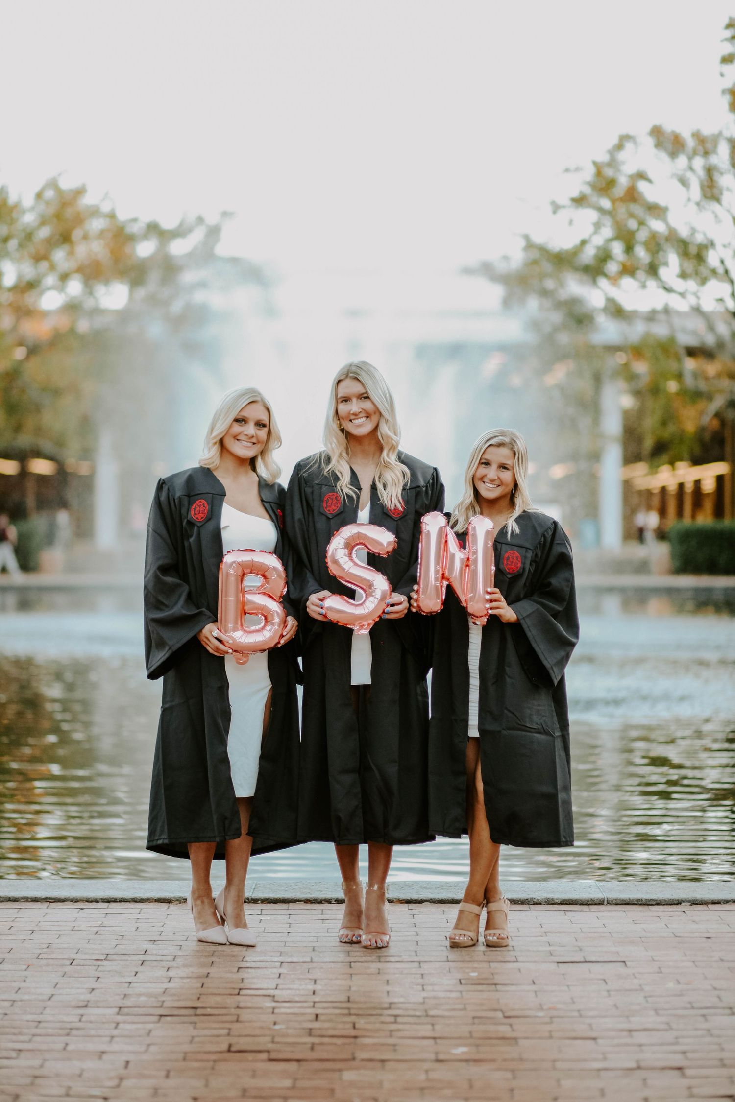 Nursing college students celebrate their BSN degrees with grad photos on their college campus.