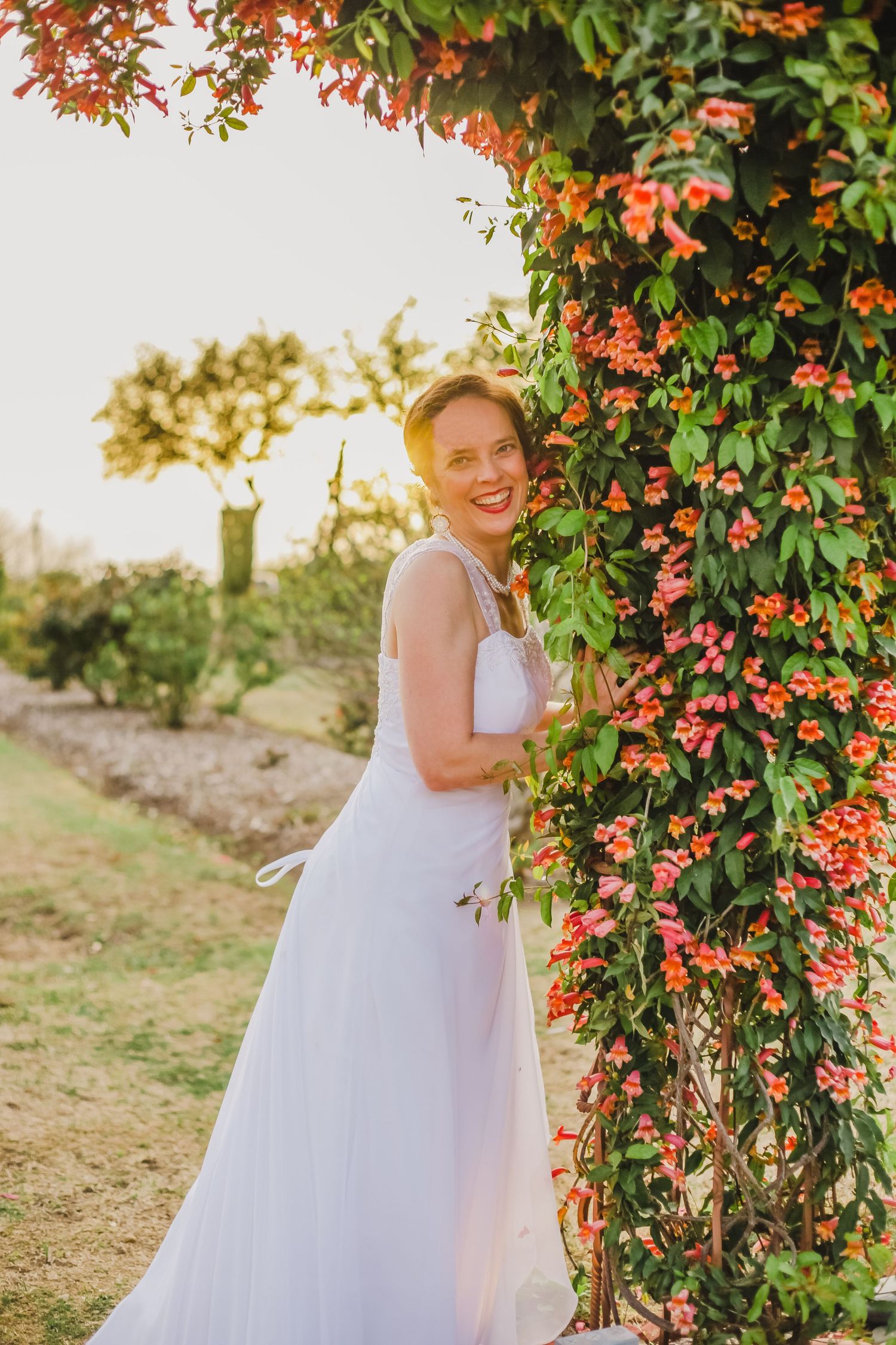 White wedding gown photographed among blooming orange flowers and green foliage.