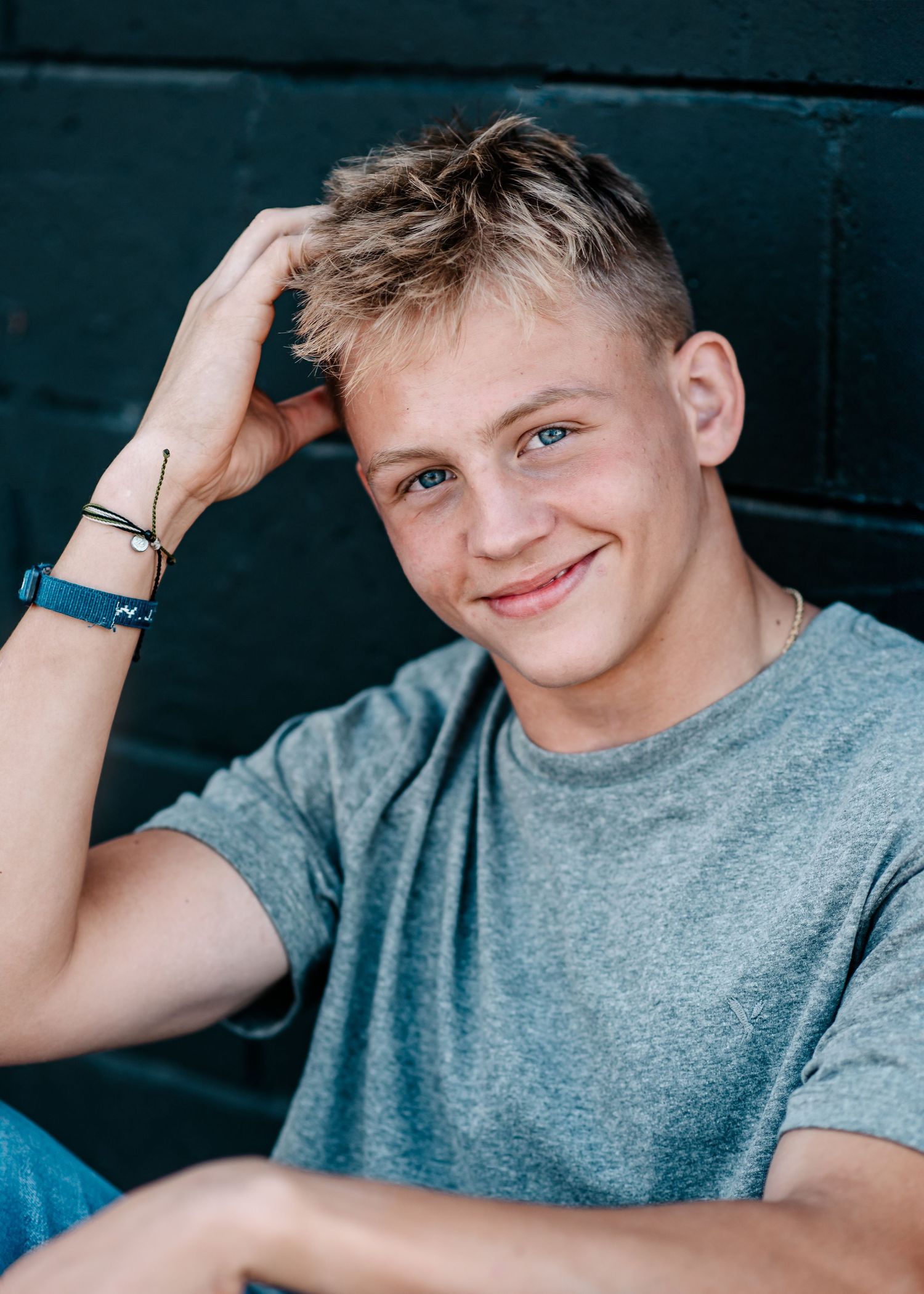 Casual portrait of student in grey t-shirt smiling against dark background.