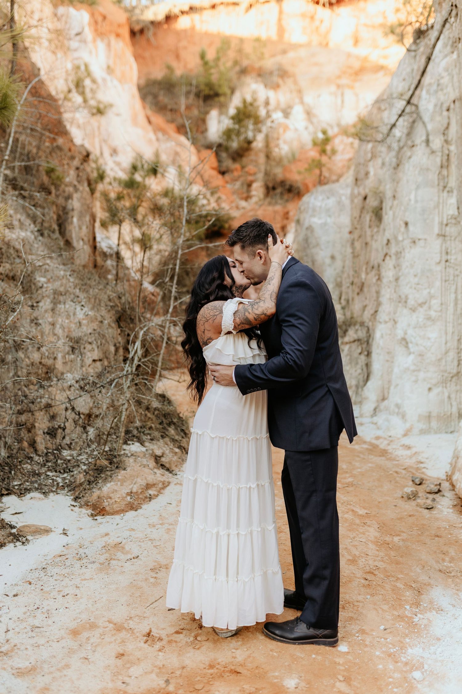 An intimate embrace between a couple in wedding attire amid towering canyon walls.