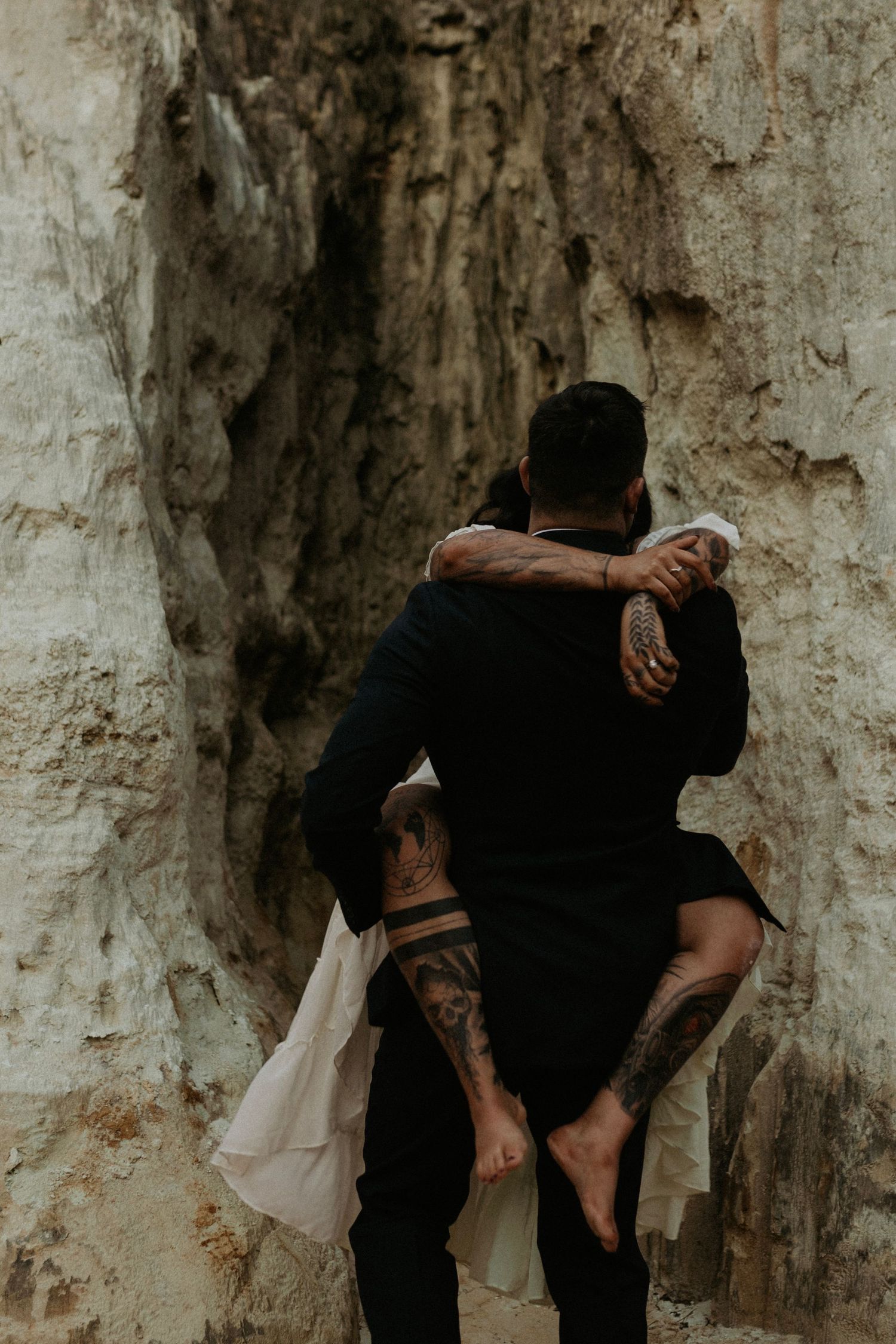 An intimate embrace against weathered limestone cliffs with dramatic shadows.