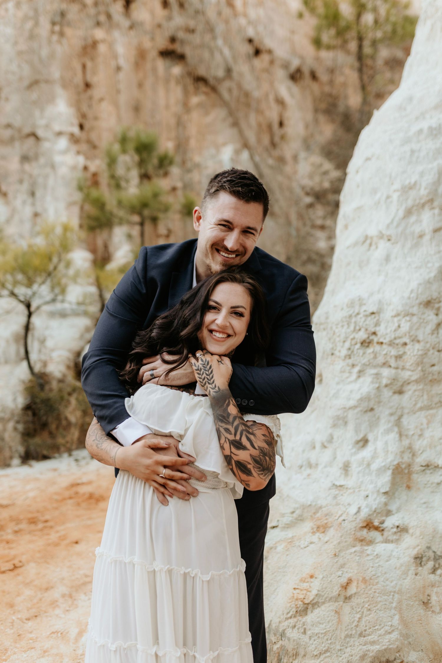 A joyful couple sharing an intimate moment in front of towering desert rock formations.