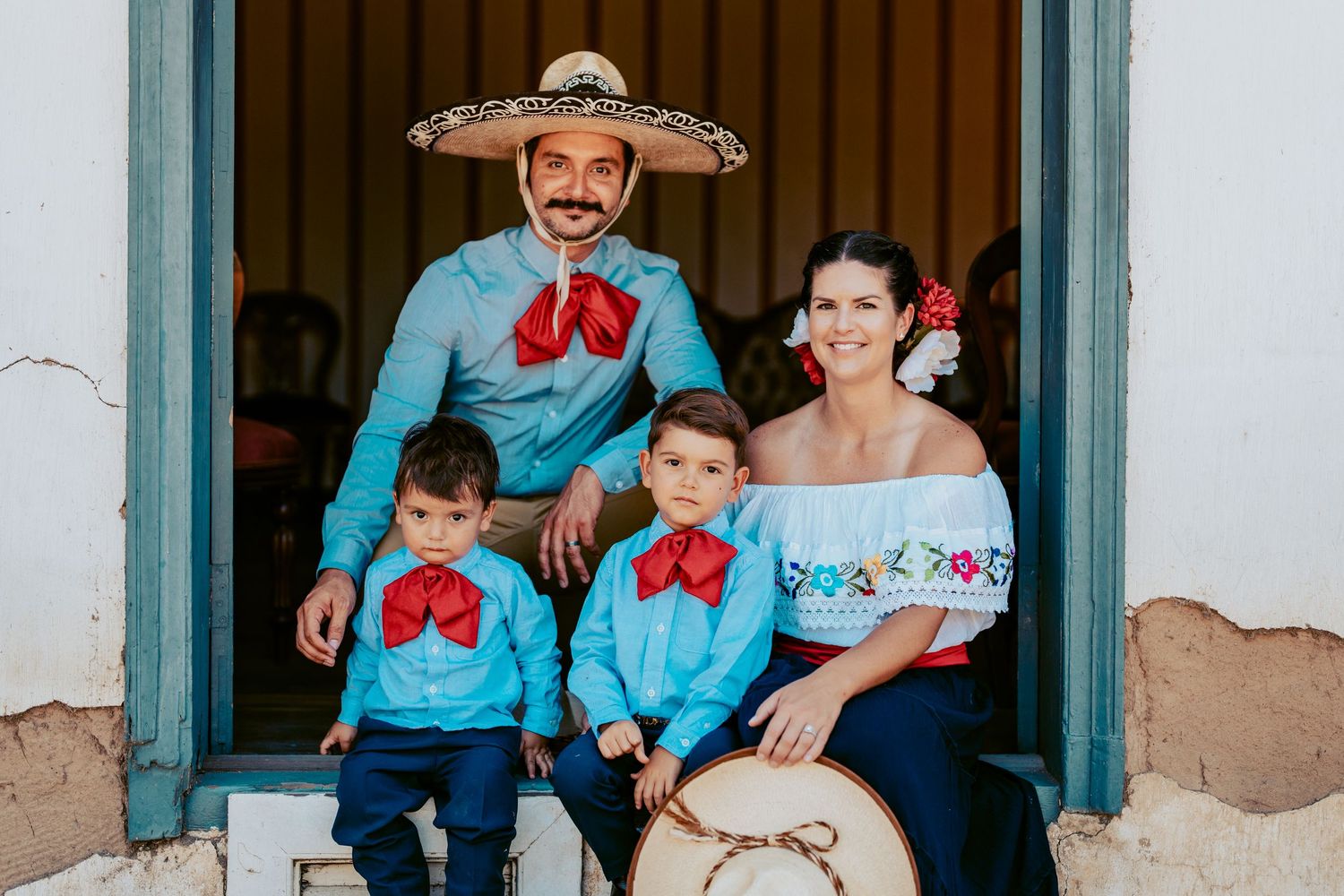 Family wearing coordinating blue and white Mexican-inspired outfits poses in doorway.