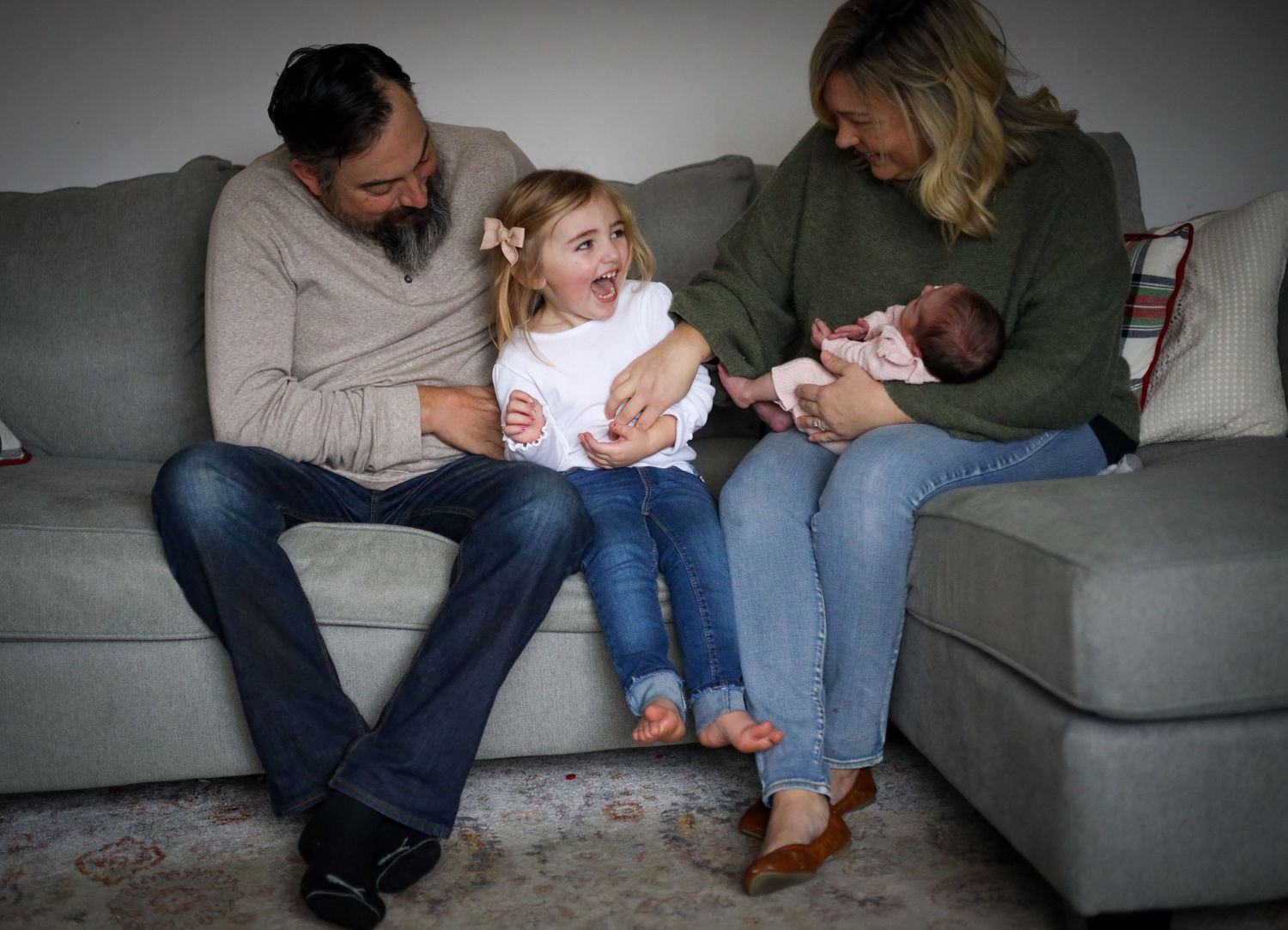 Family lifestyle session on grey couch showing casual, candid moments together.
