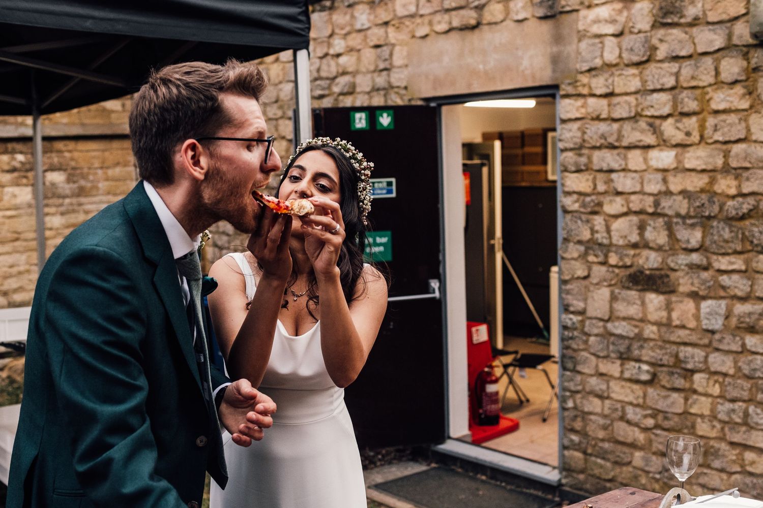 Candid moment shared between couple against stone wall exterior.