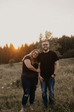Happy couple embracing in a meadow during golden hour sunset.