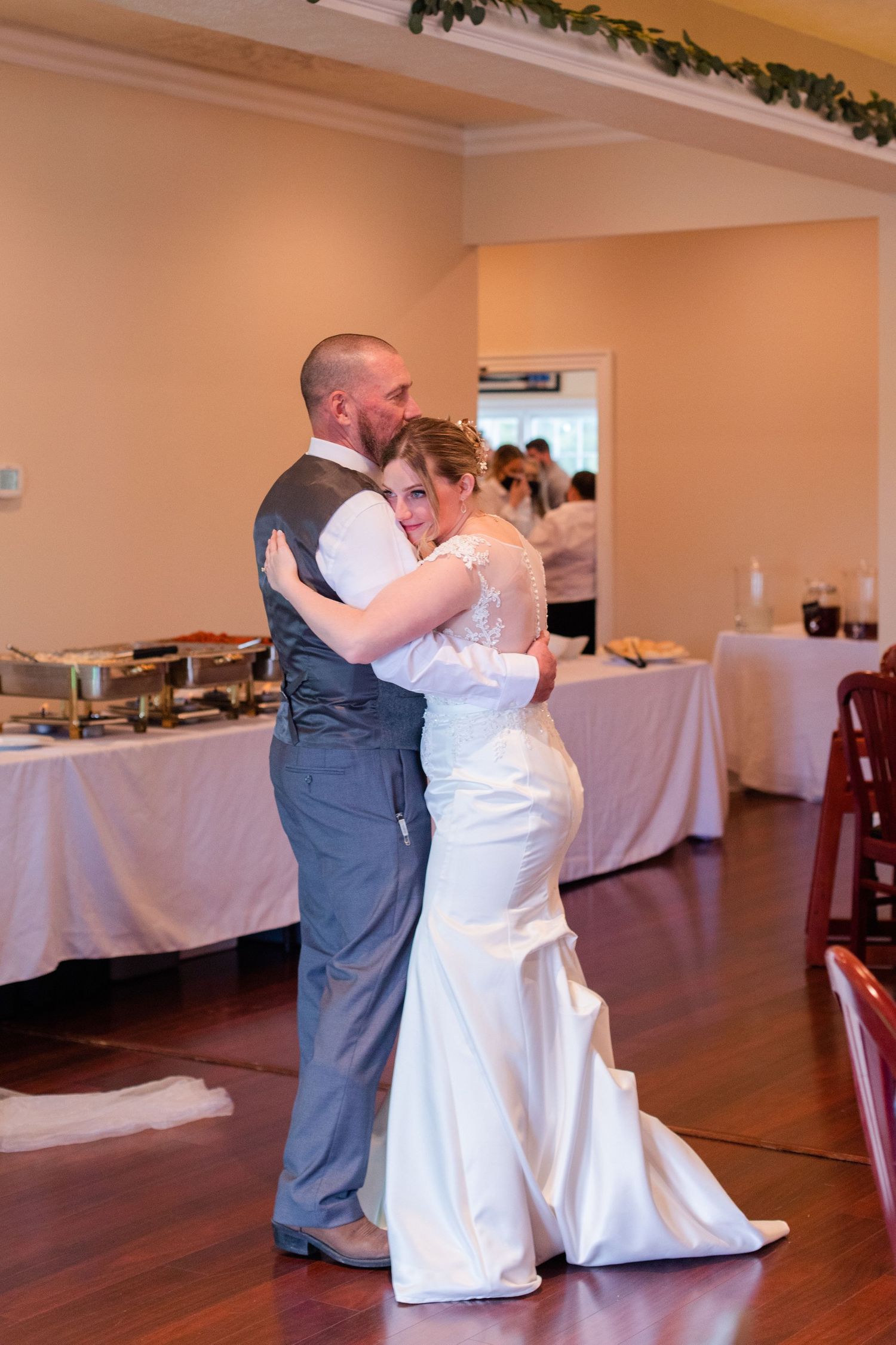 Couple shares their first dance in a reception hall with white-clothed tables.