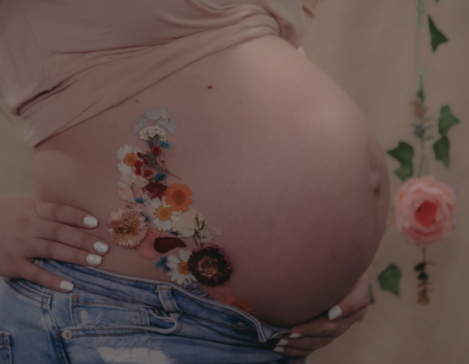 Close-up of a pregnant belly decorated with delicate floral temporary tattoos.
