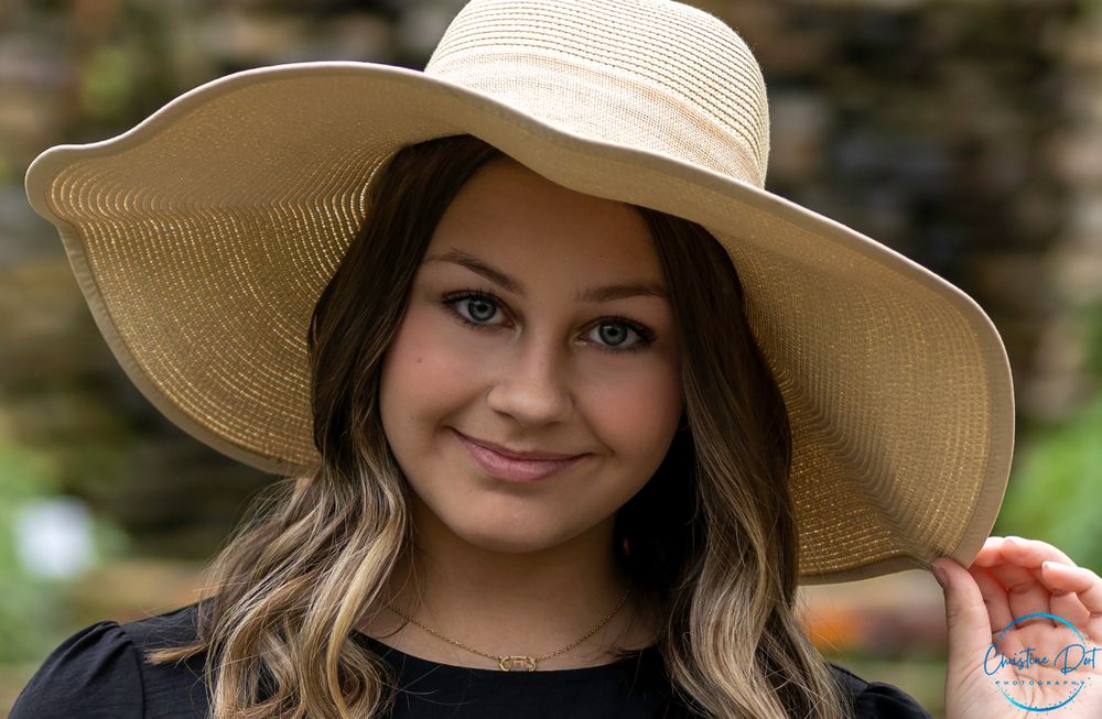Summer fashion portrait featuring a wide-brim straw hat and flowing hair outdoors.