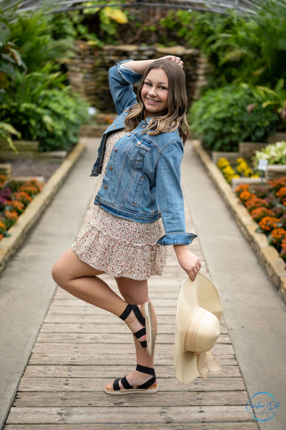 Casual style photo in a garden conservatory wearing denim jacket and floral dress.