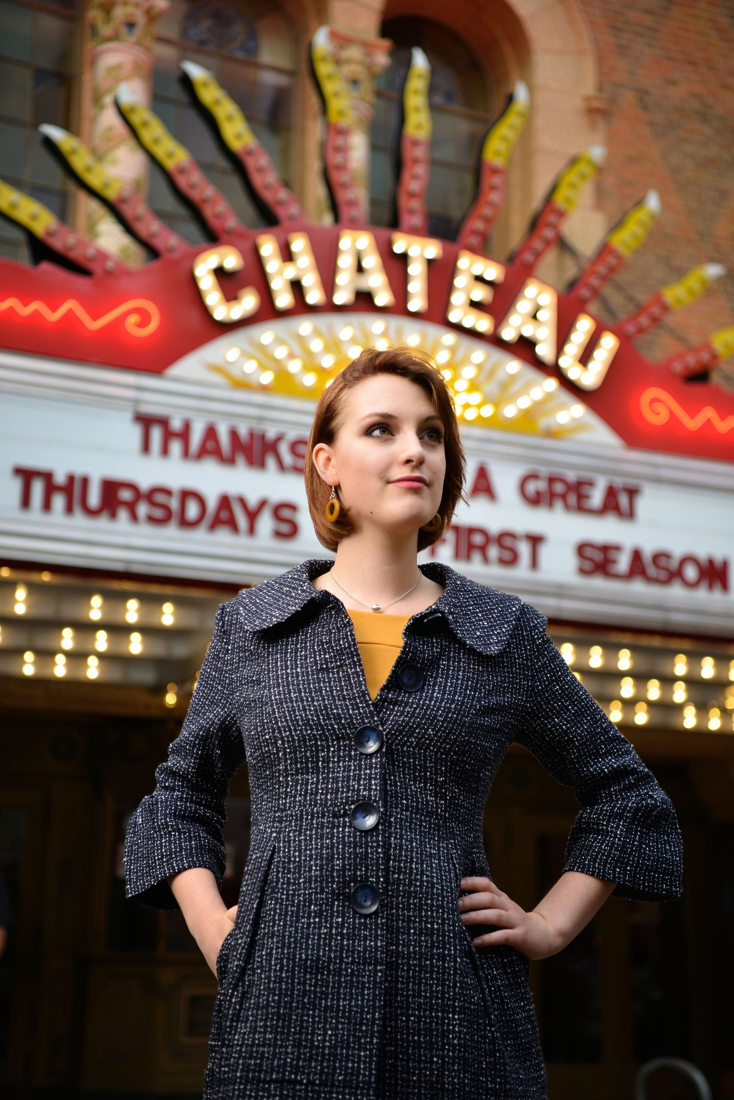 Stylish pose in front of vintage theater marquee with illuminated Chateau sign.