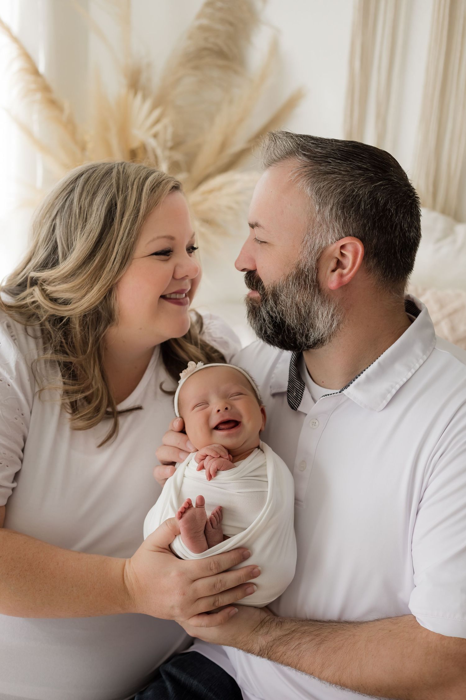 A huge grin on this swaddled newborn baby girl during her newborn portrait session in the studio.