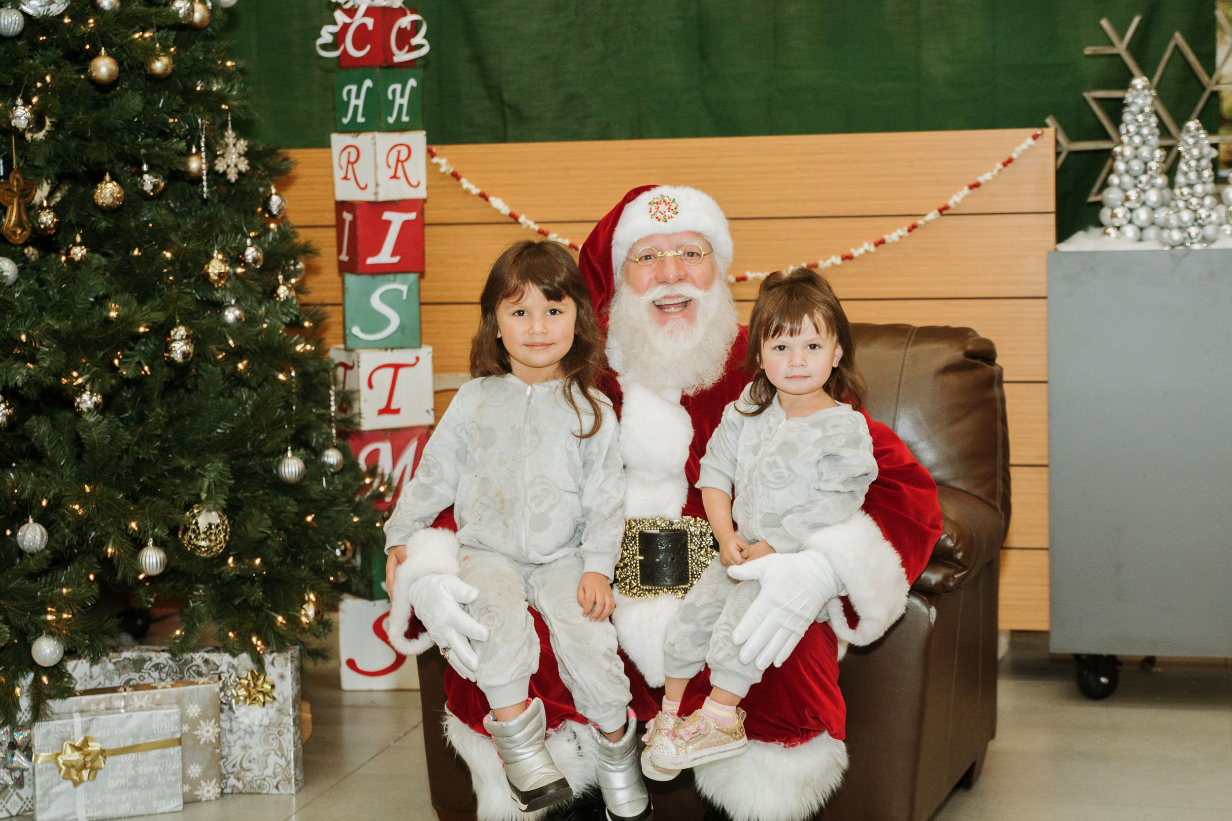 A holiday photo session with multiple children sitting with Santa Claus at a decorated Christmas venue.