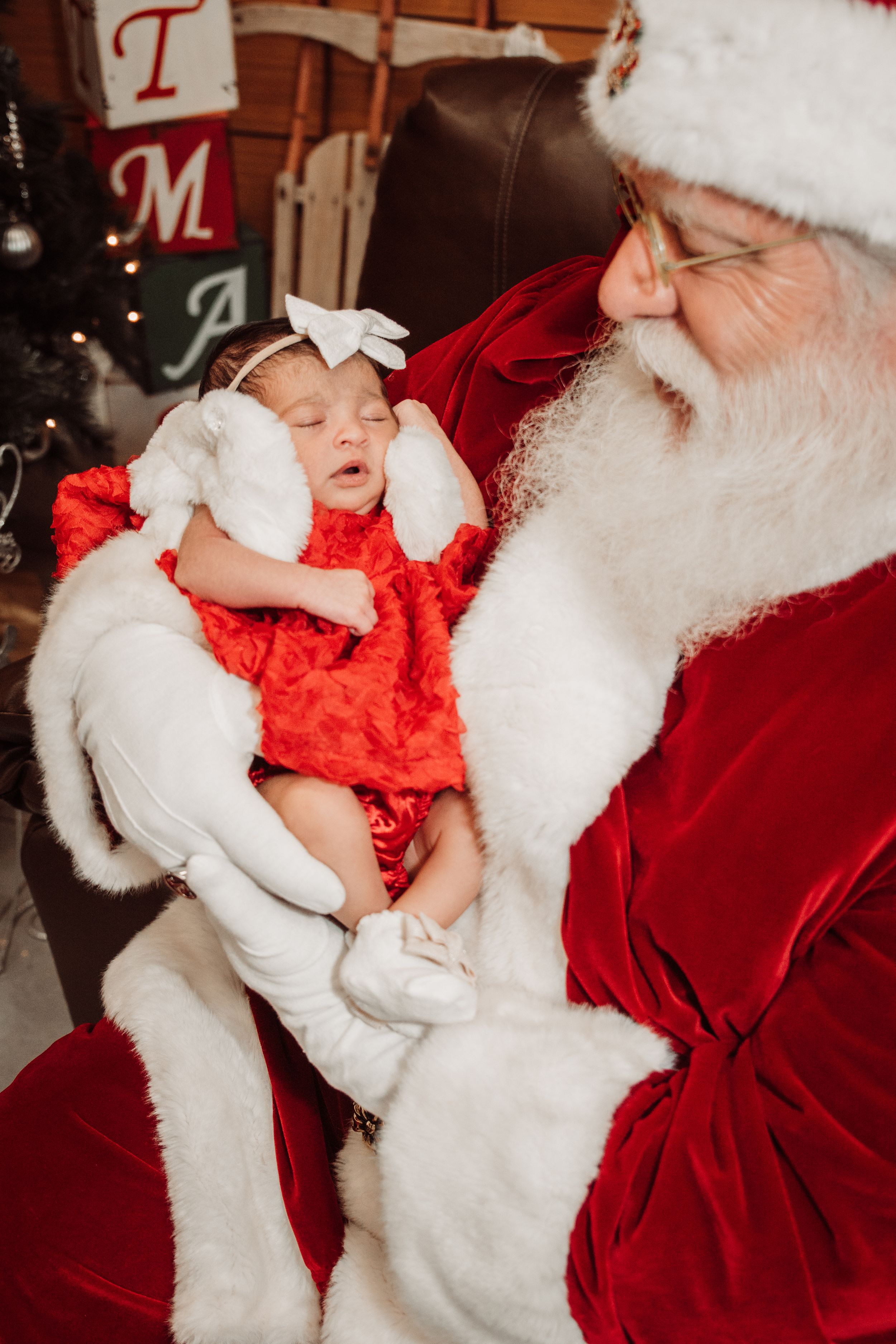 A peaceful sleeping baby in red dress during holiday photos.