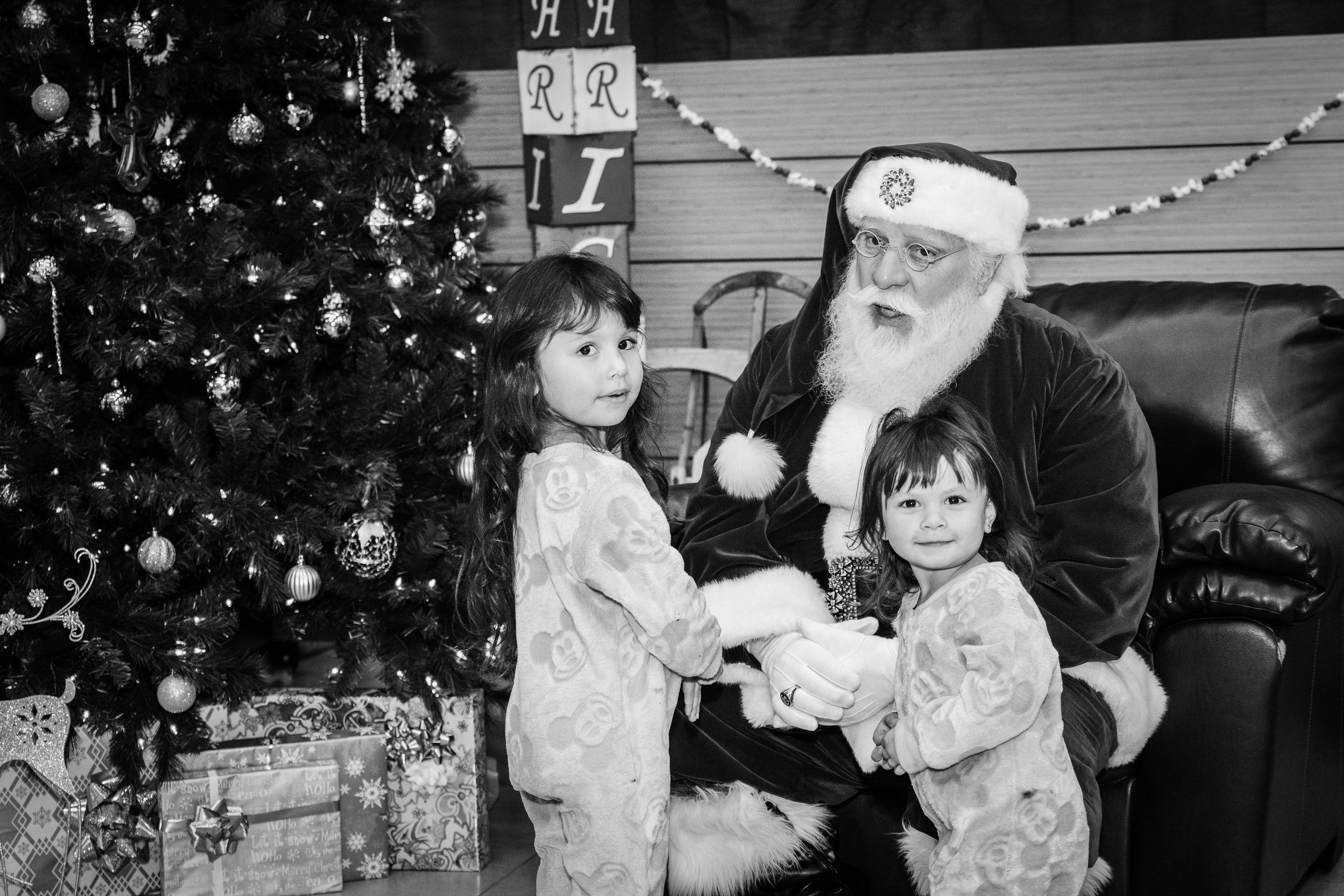 Black and white photos of children meeting Santa Claus at a Christmas event with twinkling lights.