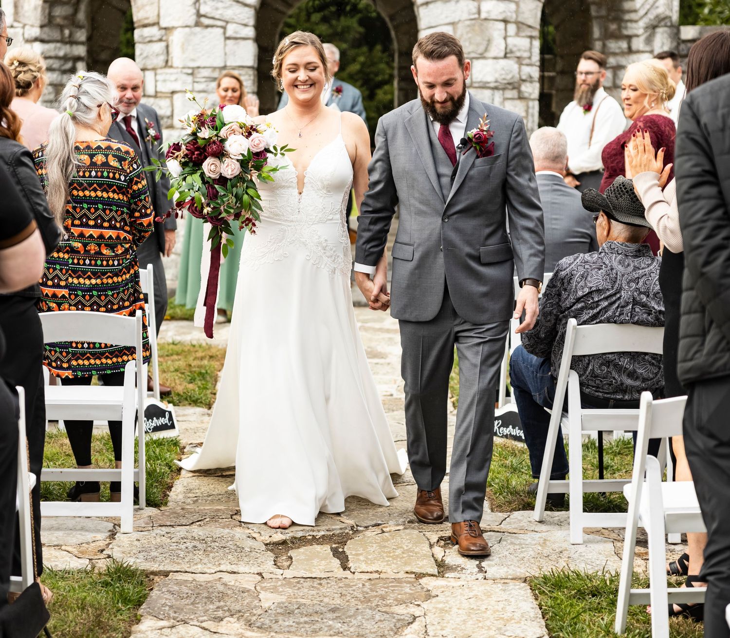 A couple walking down stone steps after their outdoor wedding ceremony.