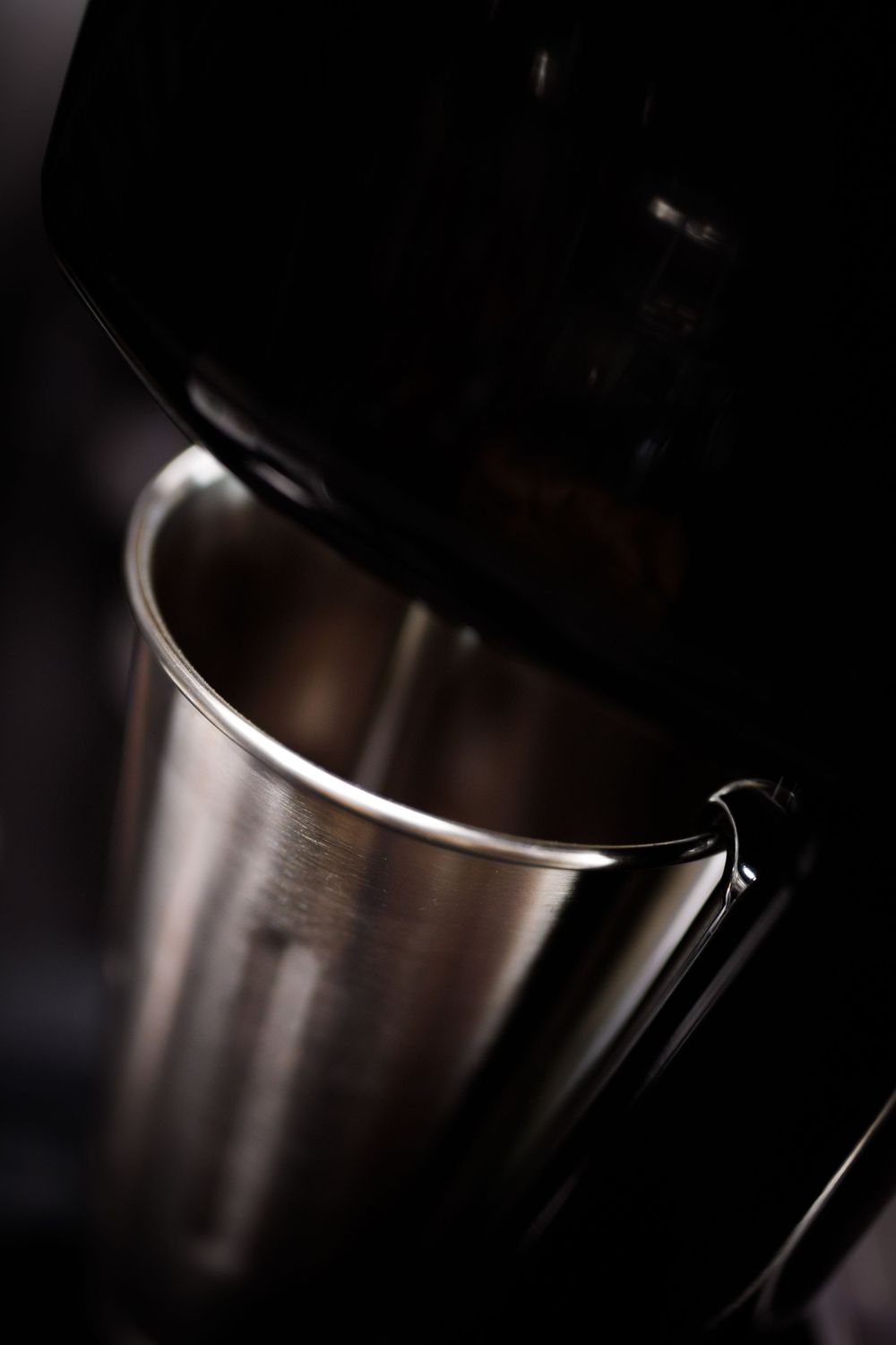Nahaufnahme eines Edelstahl Mixers in dunkler, stimmungsvoller Beleuchtung mit dramatischen Schatten.