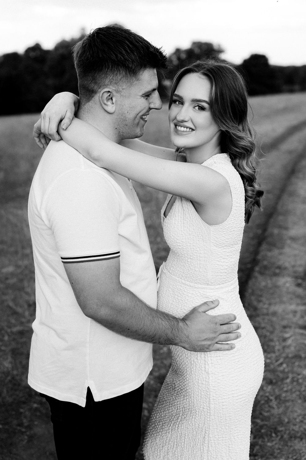 Black and white maternity portraits capture tender moments between couple in nature.