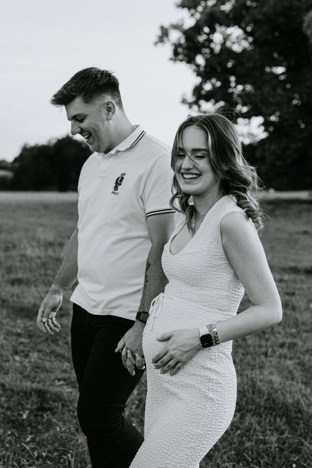 Expecting couple shares intimate outdoor maternity photoshoot moments in a sunlit field.