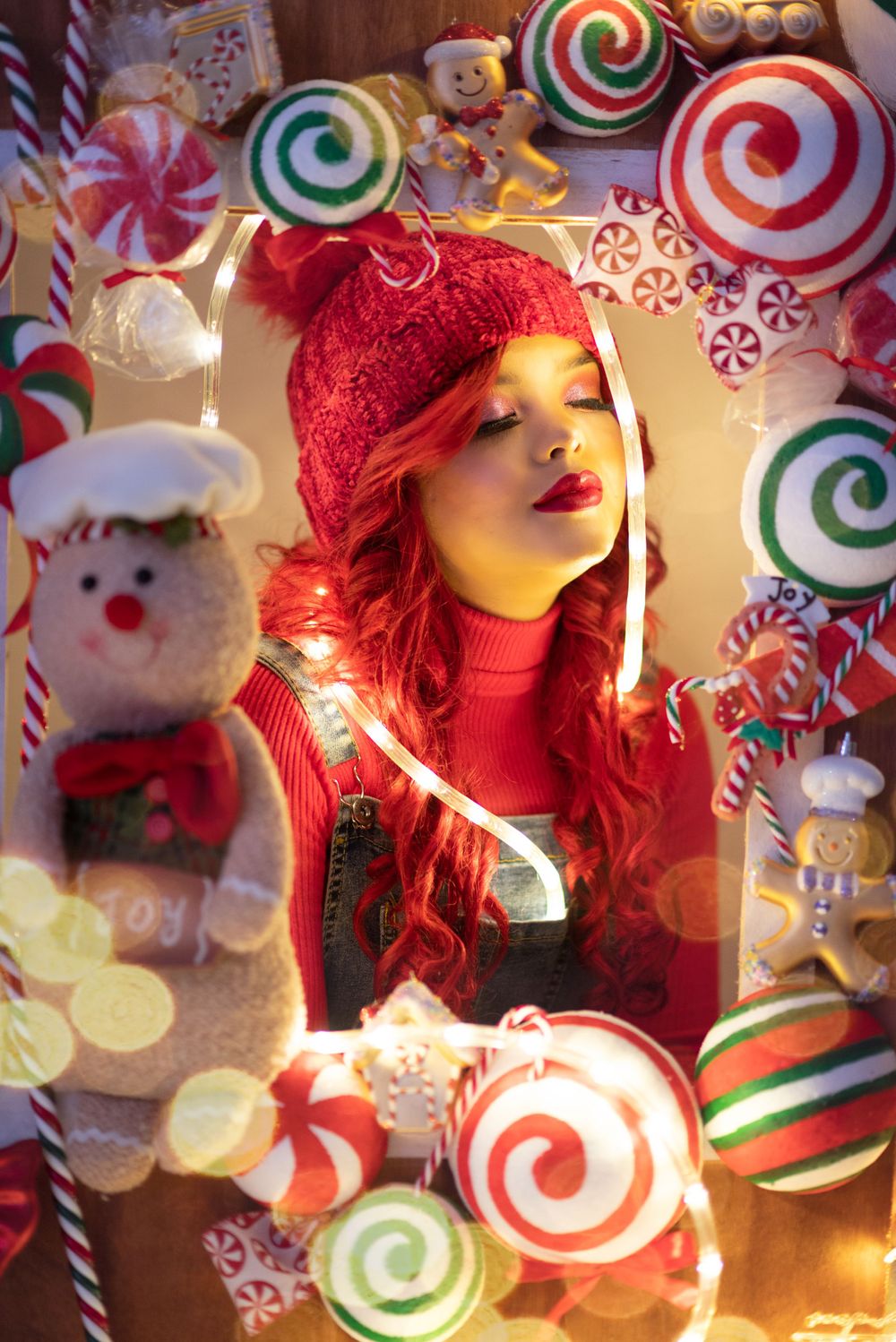 Dreamy holiday portrait surrounded by candy-themed decorations and twinkling lights.