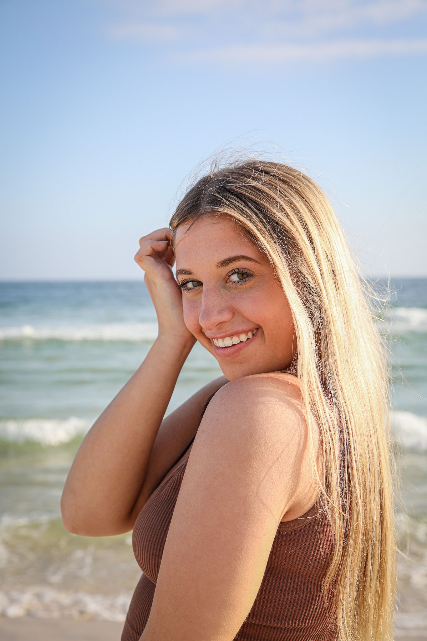 Beach portrait with ocean waves and sunny sky in background.