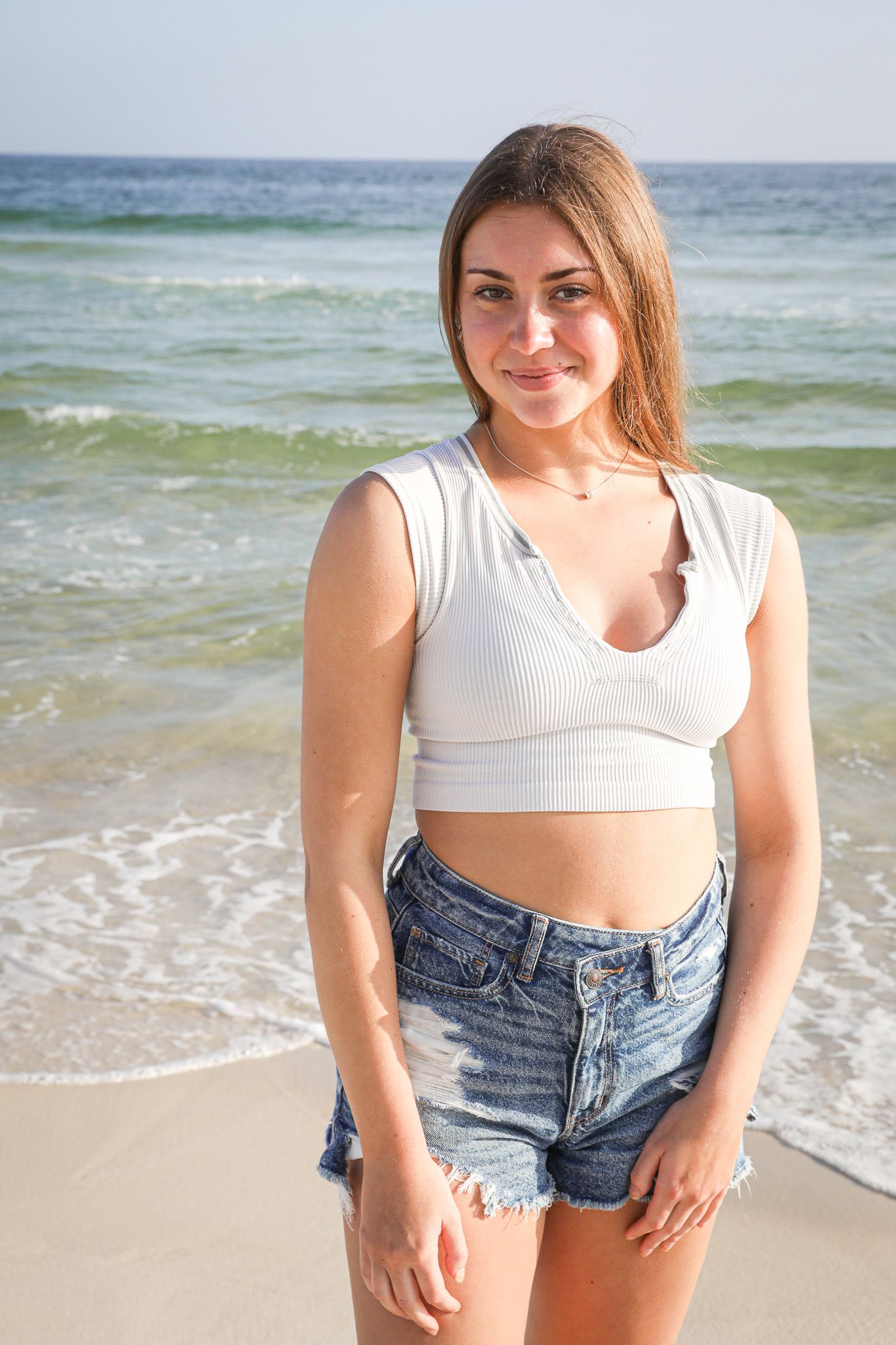 Summer beach fashion portrait with ocean waves in background.