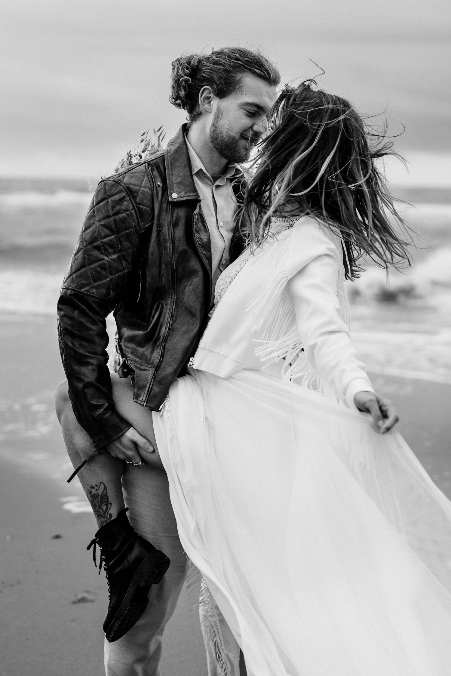 Romantic black and white beach portrait capturing an intimate moment between couple on shoreline.