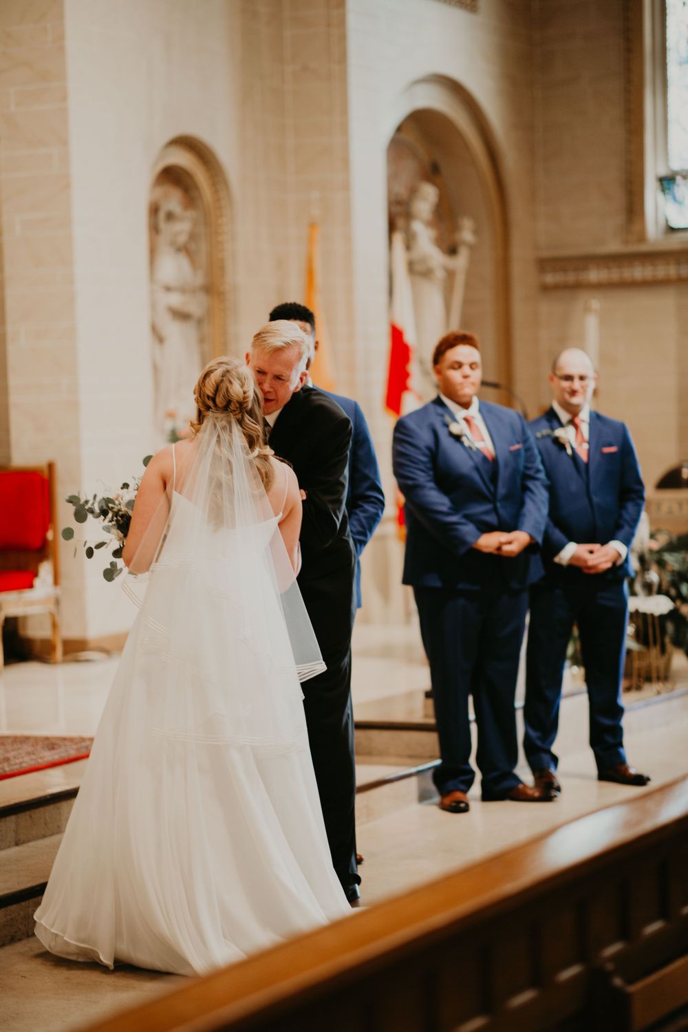 Father of bride shares tender moment with daughter at church altar before giving her away.