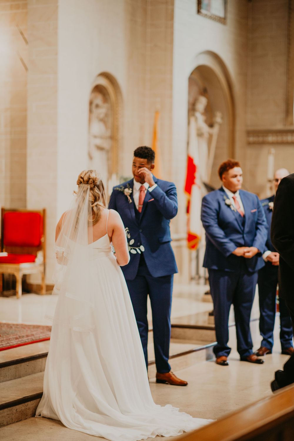 Groom wipes tears as bride approaches altar during emotional church wedding ceremony.