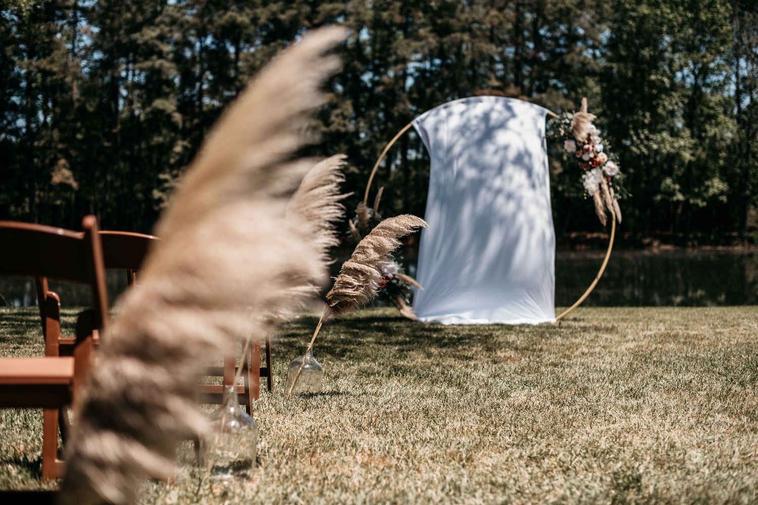 Decorative circular wedding arch with white fabric and floral arrangements in an outdoor setting.