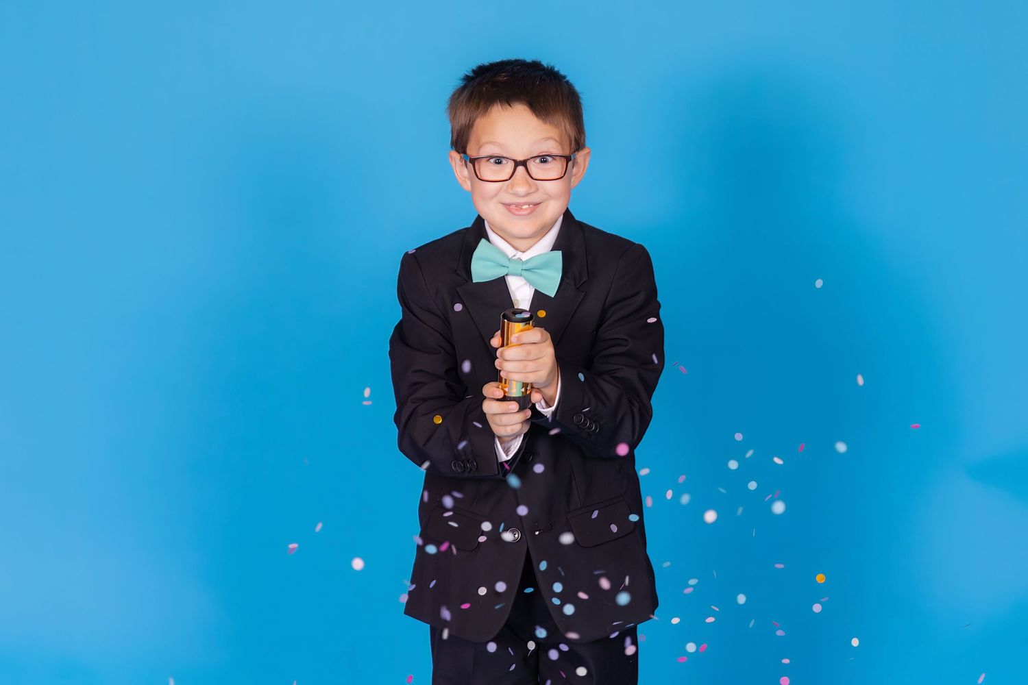 child popping confetti popper on savage blue jay backdrop with confetti in studio in clayton new jersey gloucester