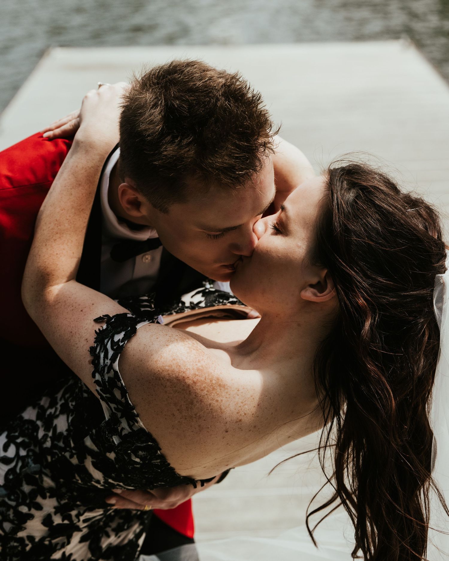 An intimate moment shared between a couple in formal attire on a dock.