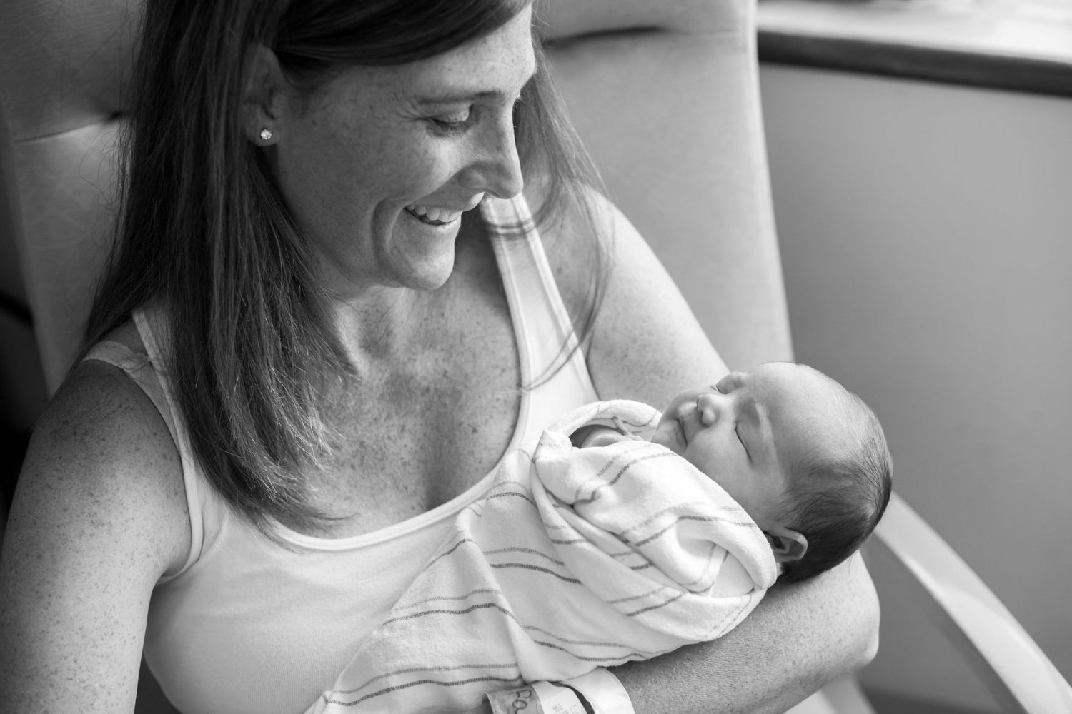 A tender black and white moment capturing a parent cradling a newborn baby in a gentle embrace.