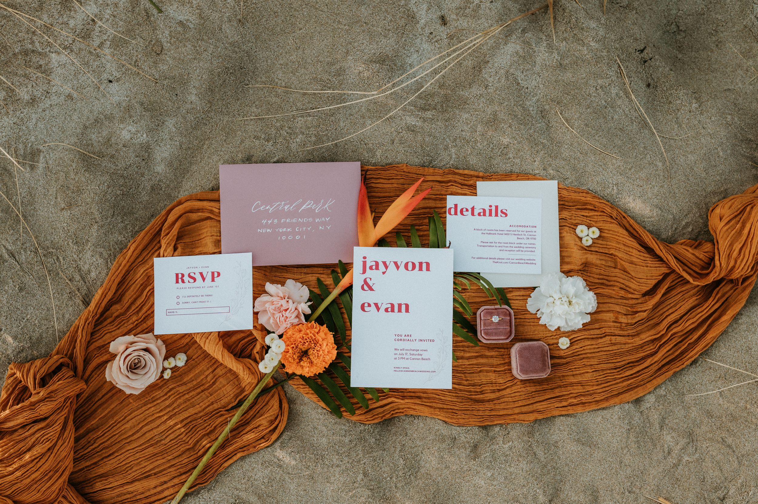 Wedding invitation suite with rust-colored fabric and floral accents on concrete background.