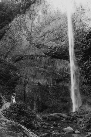 Black and white photograph of a dramatic waterfall cascading down columnar basalt cliffs.