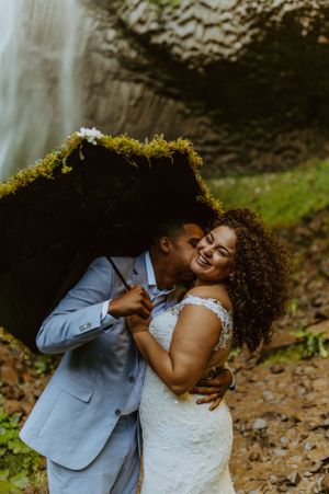 Romantic moment captured between newlyweds against a waterfall backdrop.