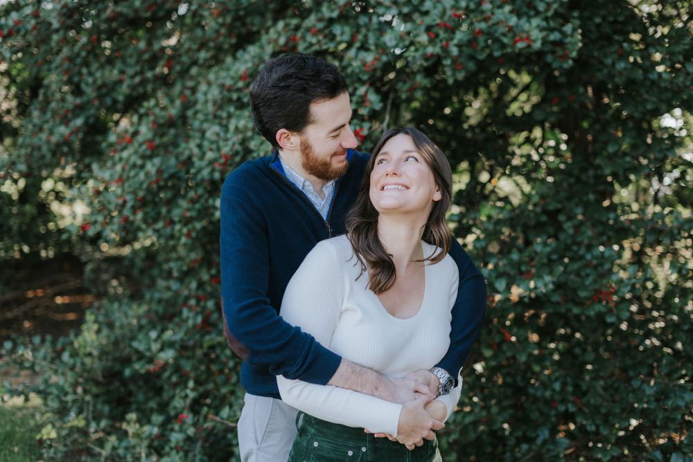 Couple sharing intimate embrace and laughter in outdoor natural setting.