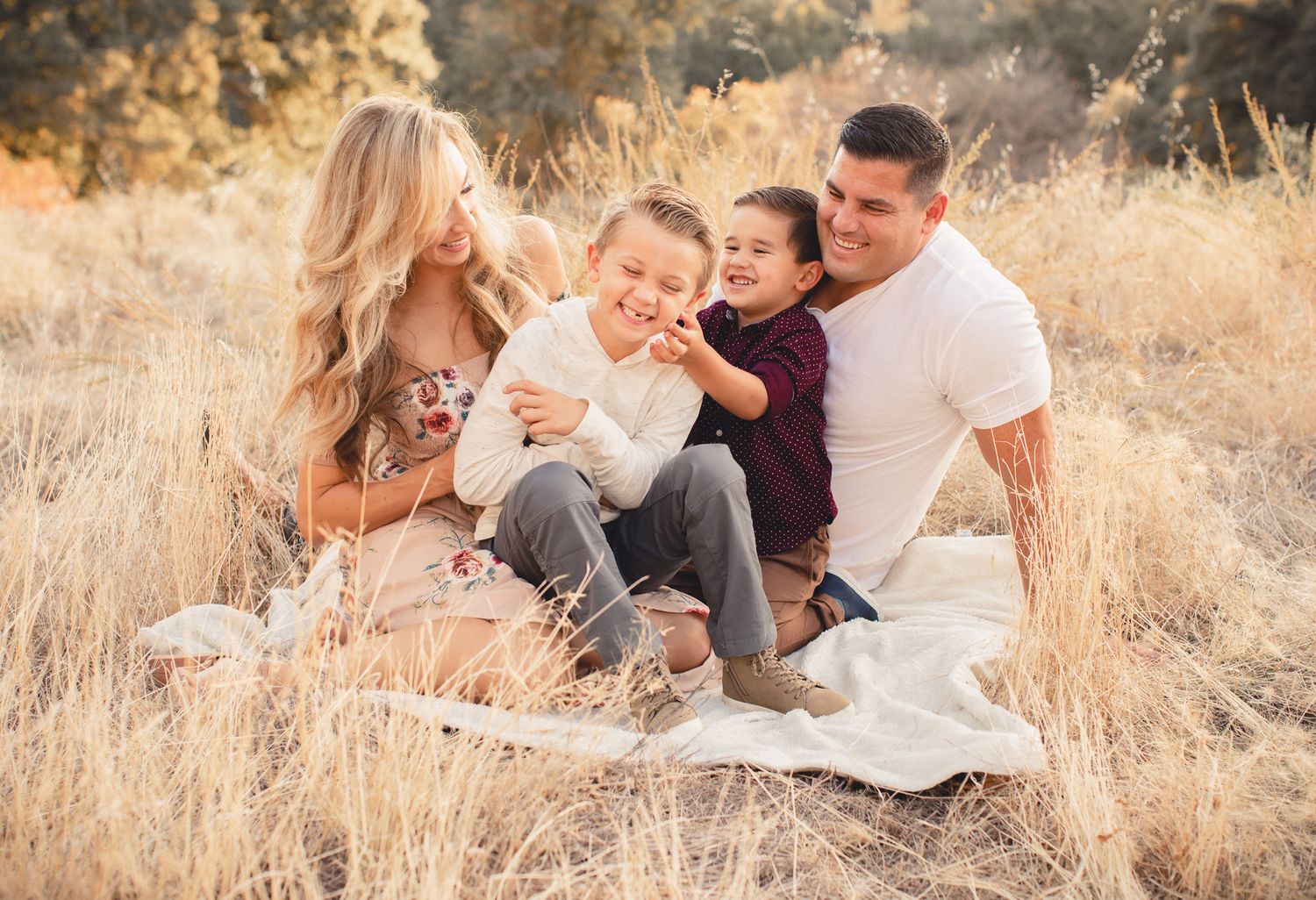 Happy family with two young children sitting together in a golden field during autumn.