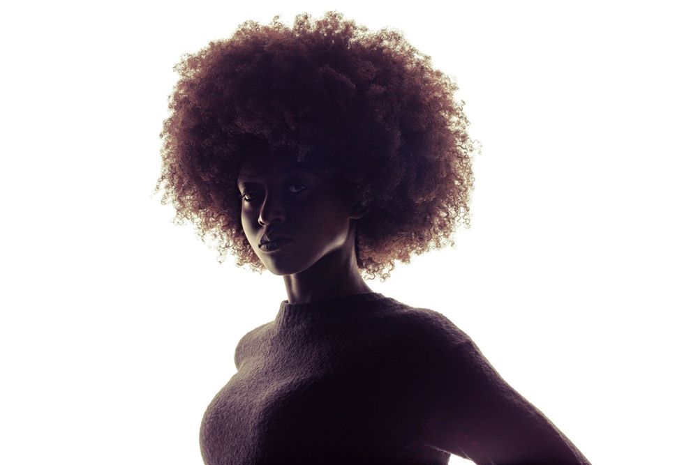 Backlit woman's Afro silhouette creating a halo effect.
