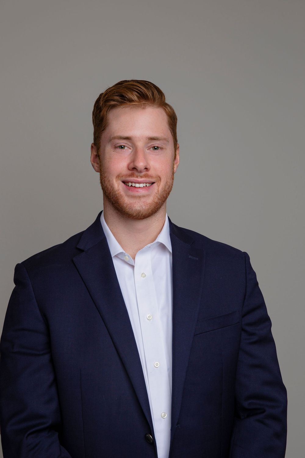 Professional headshot series showing a person in a navy suit and white shirt against a gray background.