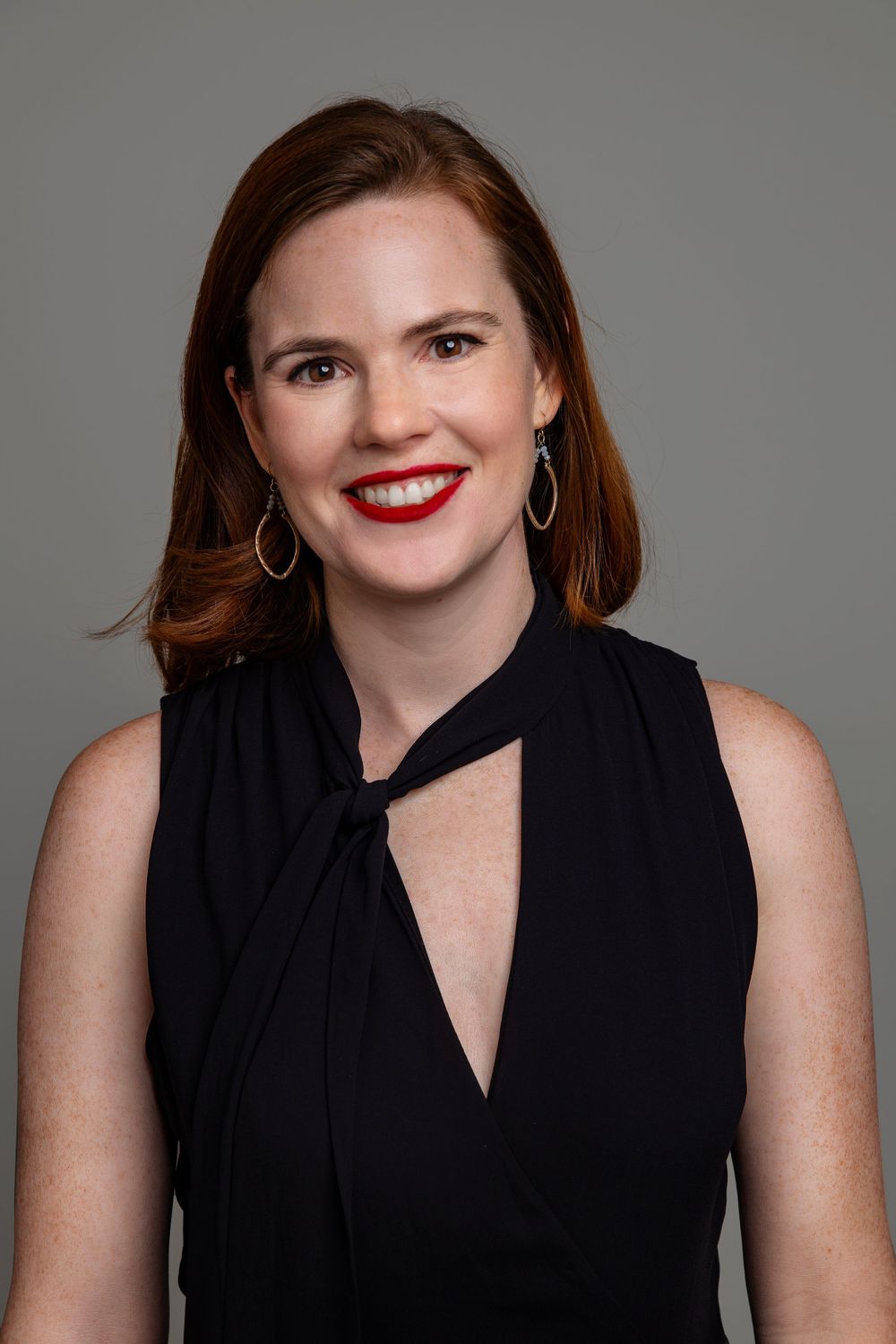 Professional portraits showing black sleeveless top and bright red lipstick against gray background.