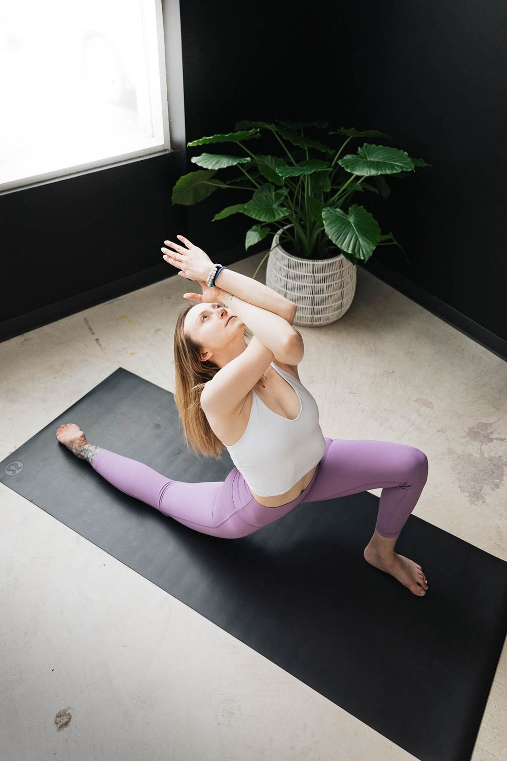 Modern yoga flow sequence demonstrated on black mat with minimalist studio backdrop.