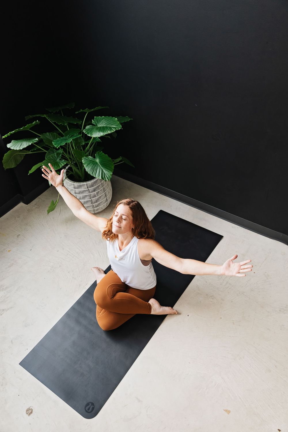 Flowing yoga sequence demonstrated with potted plant accent in minimalist setting.