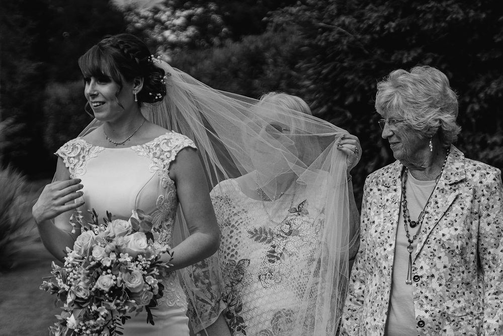 Black and white wedding photo showing a bride with veil holding a floral bouquet.